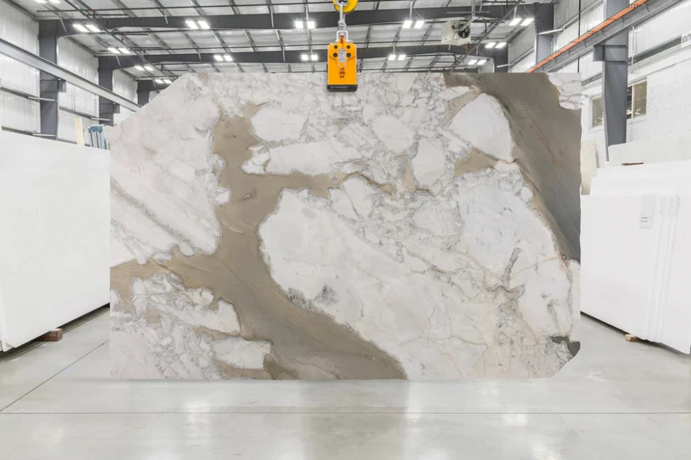 Large white marble slab with grey and gold veining in indoor slab yard
