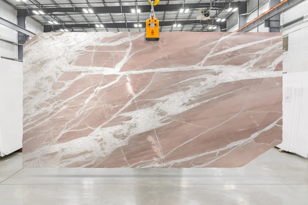 Large quartzite slab with pink and white veins in a warehouse setting