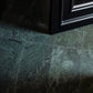 Close-up of a green marble floor tile with a black frame in the corner.