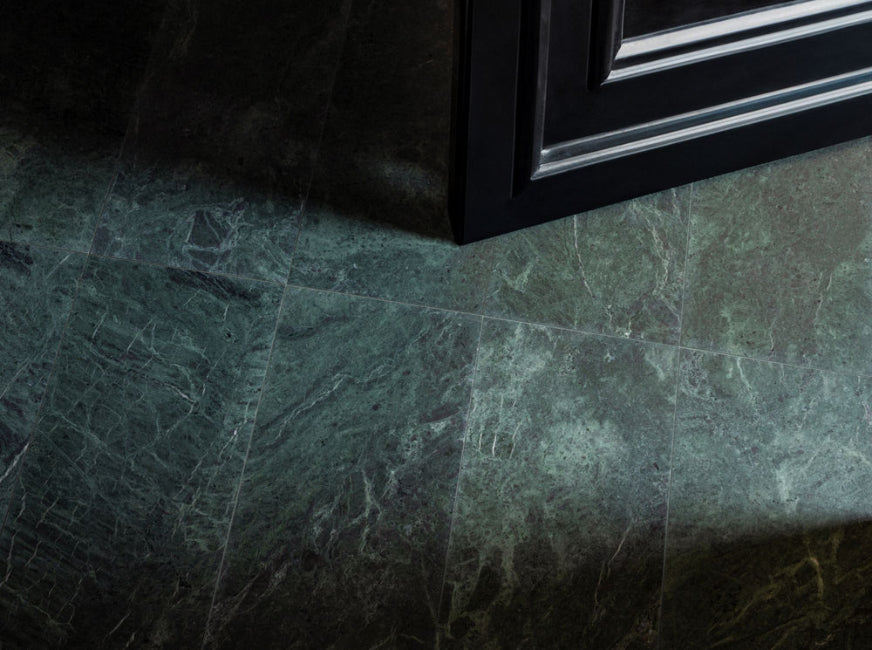Close-up of a green marble floor tile with a black frame in the corner.
