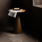 Wooden side table with a white towel and bar of soap and a dark brown marble tile floor