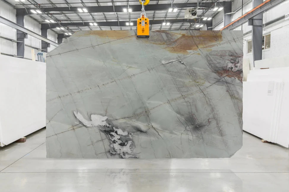 Green marble slab with grey and orange veining in indoor slab yard