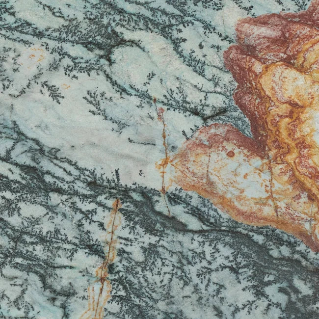 A close-up of a quartzite stone surface with a mottled pattern of pale blue-green, gray, and rust-orange veining.