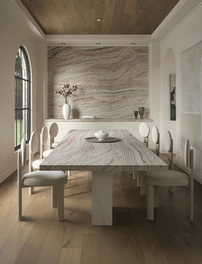 Modern dining room with travertine table and chairs, stone wall, and large window.