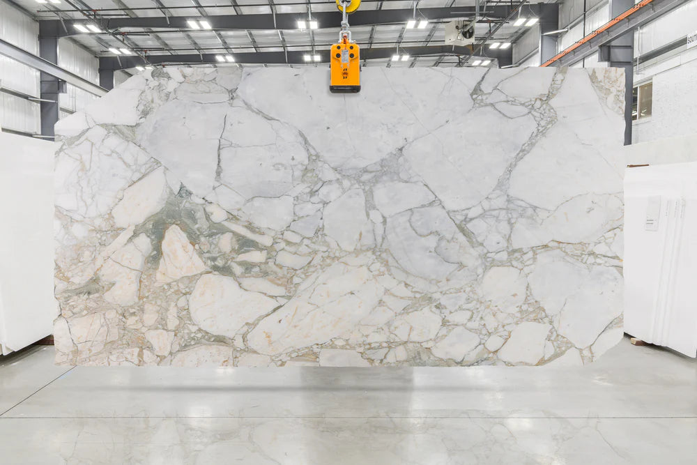 white marble with green and gold veining in slab yard